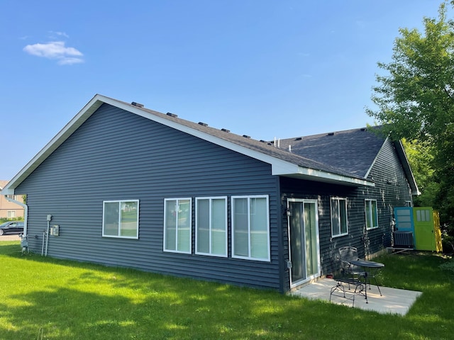back of house featuring a yard, a patio, and roof with shingles