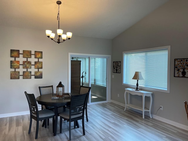 dining room with a notable chandelier, wood finished floors, baseboards, and vaulted ceiling