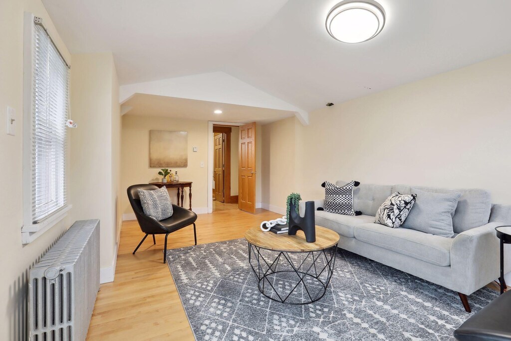 2733 Columbus Ave, Minneapolis, MN 55407 - living room with radiator heating unit, baseboards, lofted ceiling, and light wood finished floors