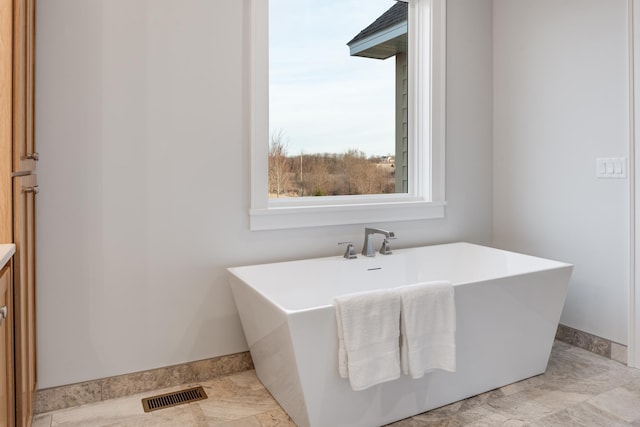 bathroom featuring a freestanding tub, visible vents, vanity, and baseboards