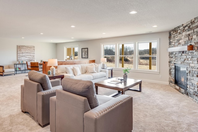 living area featuring a textured ceiling, baseboards, recessed lighting, light colored carpet, and a fireplace