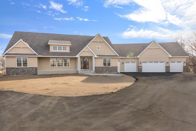 craftsman-style home with roof with shingles, driveway, stone siding, an attached garage, and board and batten siding