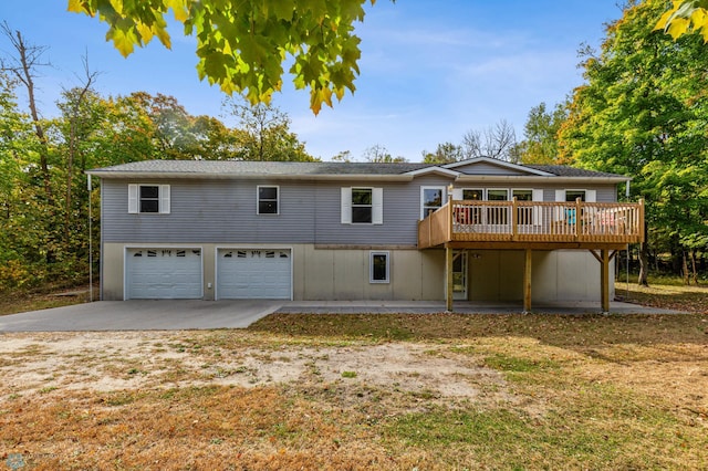 back of property featuring a garage, a deck, and concrete driveway