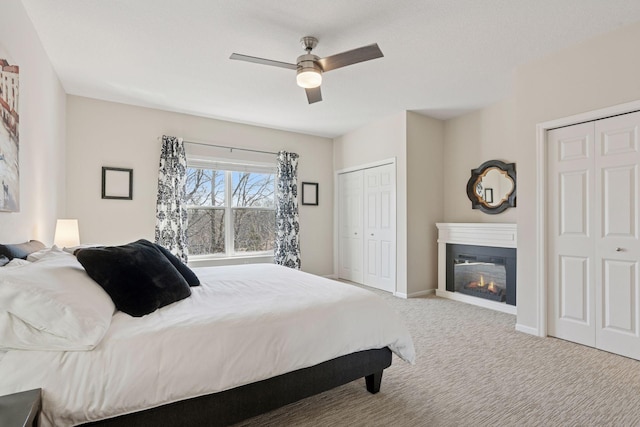 17785 Valley Cove Ct, Minnetonka, MN 55345 - carpeted bedroom featuring multiple closets, a glass covered fireplace, a ceiling fan, and baseboards