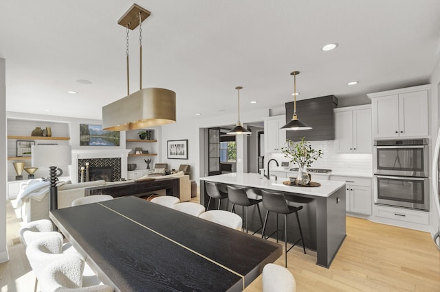 9195 Eagle Ridge Rd, Chanhassen, MN 55317 - kitchen with double oven, light wood-type flooring, light countertops, a kitchen breakfast bar, and recessed lighting