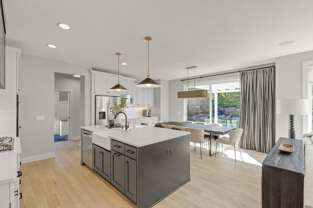 9195 Eagle Ridge Rd, Chanhassen, MN 55317 - kitchen featuring a sink, stainless steel appliances, light wood finished floors, light countertops, and white cabinetry