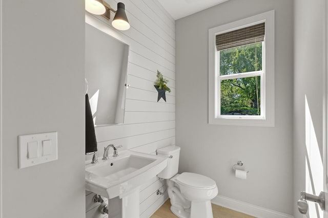 9195 Eagle Ridge Rd, Chanhassen, MN 55317 - half bathroom featuring toilet, wood finished floors, wooden walls, and a sink