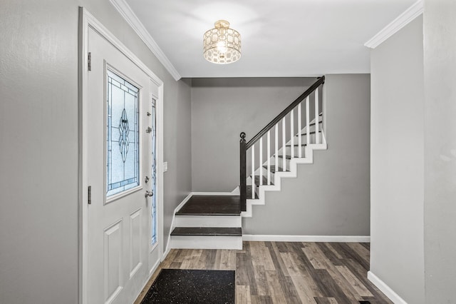 foyer entrance featuring crown molding, a chandelier, stairs, baseboards, and wood finished floors