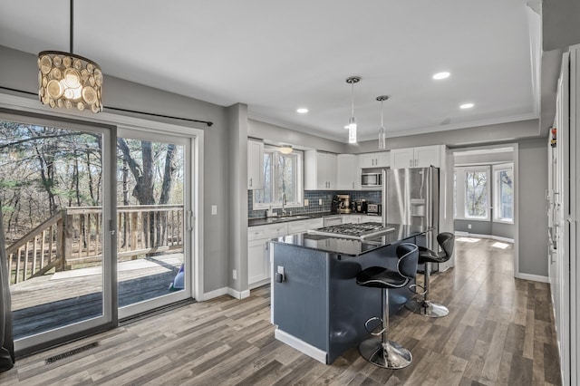 kitchen with visible vents, dark countertops, a breakfast bar, stainless steel appliances, and white cabinetry