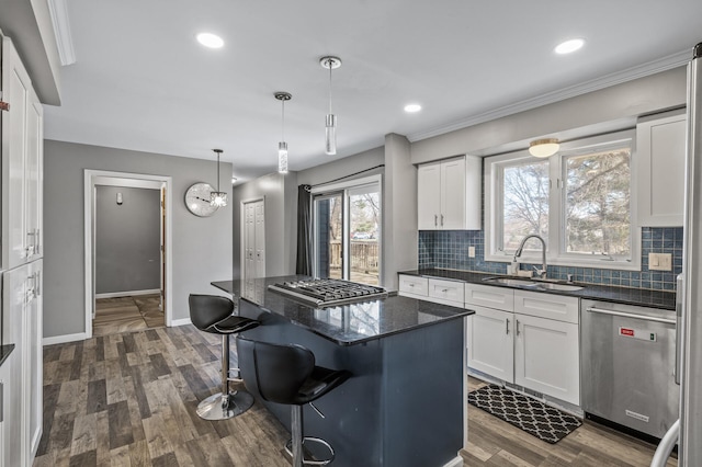 kitchen featuring decorative backsplash, a breakfast bar area, a sink, white cabinets, and stainless steel appliances