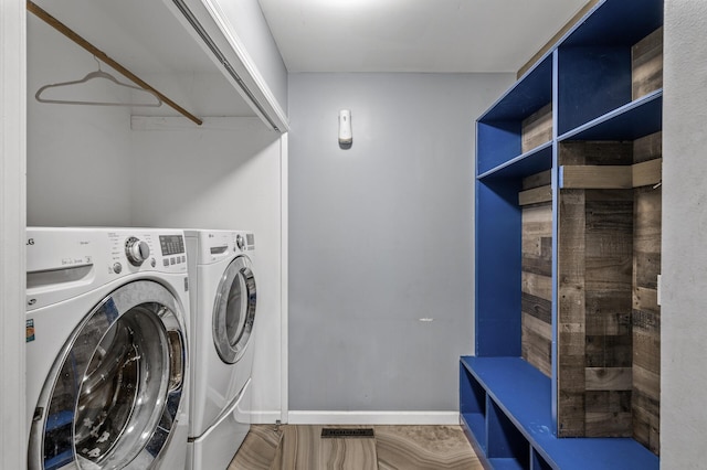 washroom featuring laundry area, baseboards, and washer and dryer