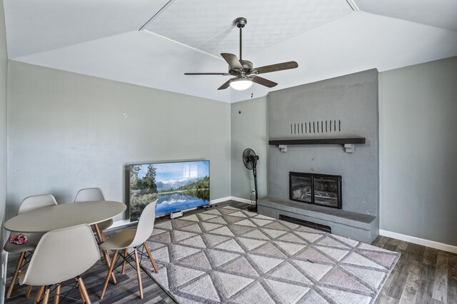 living room featuring a ceiling fan, baseboards, a fireplace with raised hearth, and wood finished floors