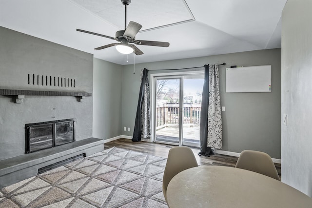 living room with a ceiling fan, baseboards, a glass covered fireplace, and wood finished floors