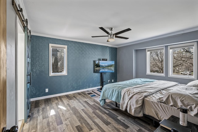 bedroom featuring crown molding, a barn door, a ceiling fan, baseboards, and wood finished floors