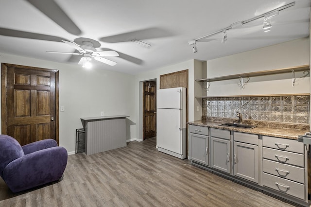kitchen featuring open shelves, tasteful backsplash, a sink, freestanding refrigerator, and light wood-type flooring
