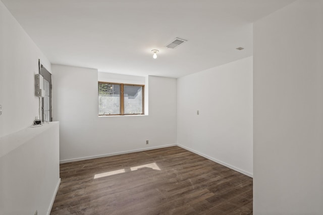 empty room featuring baseboards, wood finished floors, and visible vents