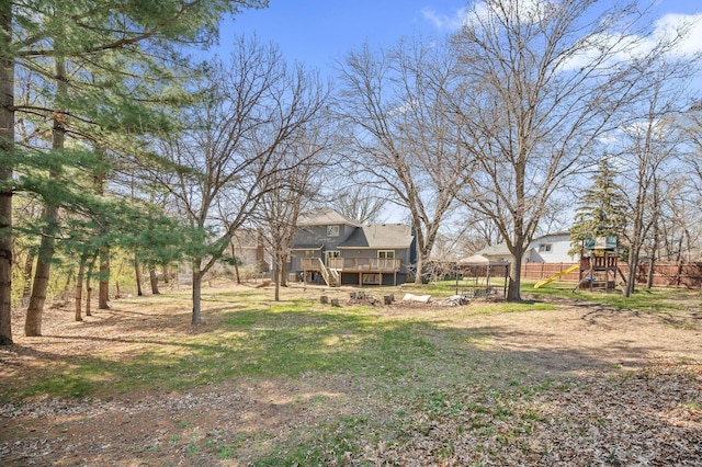 view of yard with a deck, fence, and a playground