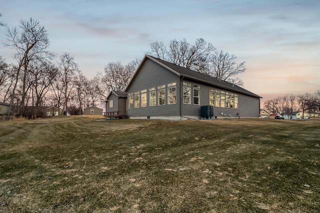 property exterior at dusk with central air condition unit and a lawn