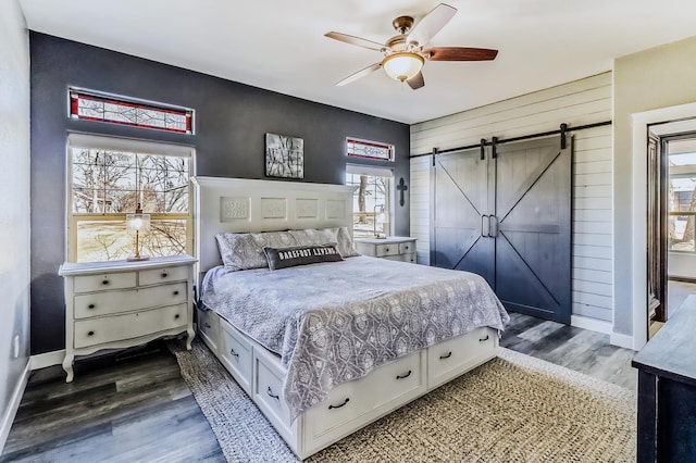 bedroom with baseboards, a barn door, a ceiling fan, and dark wood-type flooring