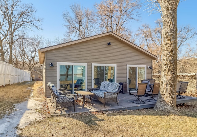 back of property with an outdoor living space, a wooden deck, and fence