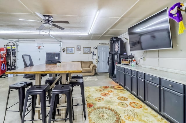 kitchen with a ceiling fan, light countertops, and concrete flooring