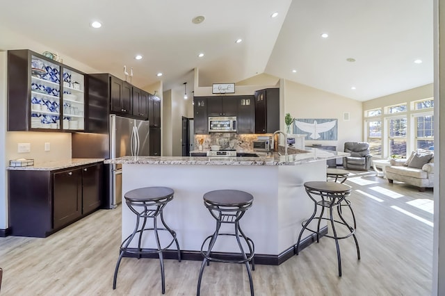46747 Poss Beach Rd, Pelican Rapids, MN 56572 - kitchen featuring stainless steel appliances, a kitchen breakfast bar, light stone counters, light wood-style flooring, and high vaulted ceiling