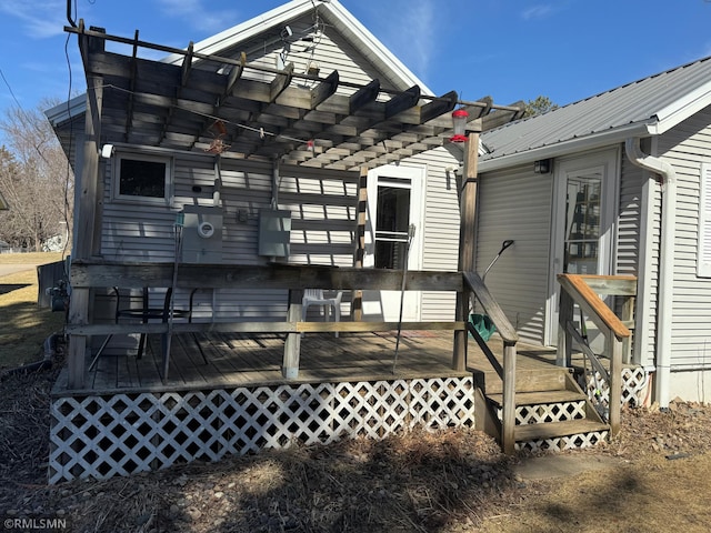 rear view of house featuring a wooden deck, a pergola, and metal roof