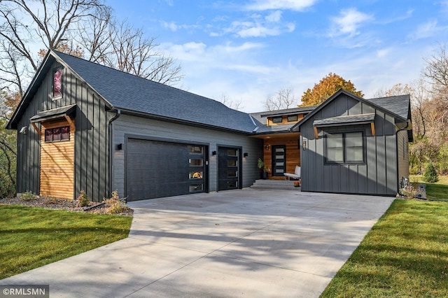 view of front of house with an attached garage, board and batten siding, a front yard, and concrete driveway