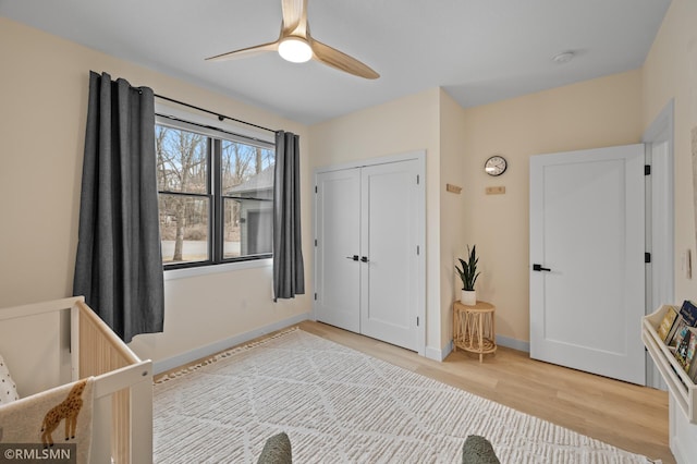 bedroom featuring light wood-type flooring, baseboards, ceiling fan, and a closet