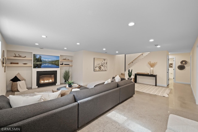 living area with recessed lighting, baseboards, a glass covered fireplace, and stairway