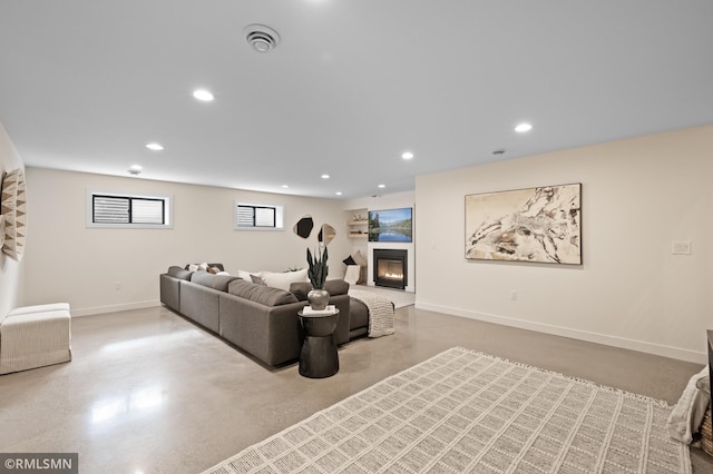 living area with recessed lighting, baseboards, a glass covered fireplace, and finished concrete flooring