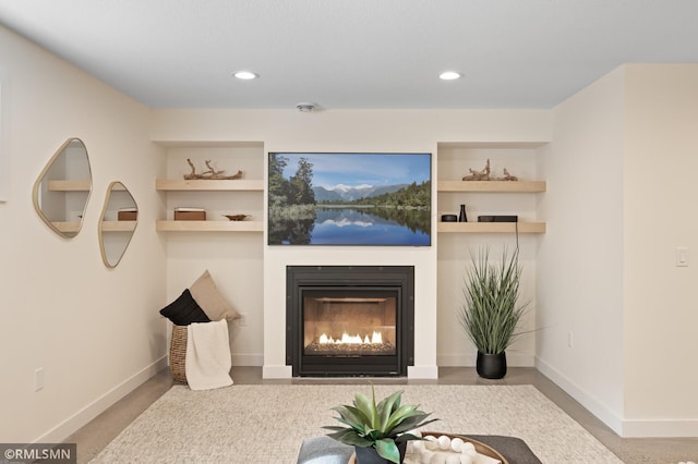 living room featuring a glass covered fireplace, baseboards, and recessed lighting