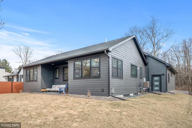 view of front of house with a shingled roof, fence, and a front yard