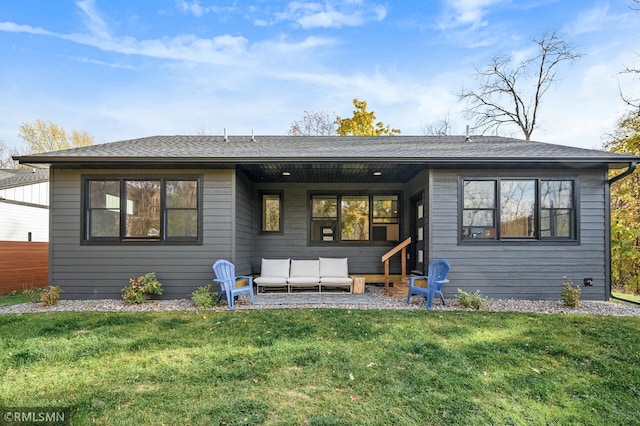 rear view of house featuring a lawn, a shingled roof, and an outdoor hangout area