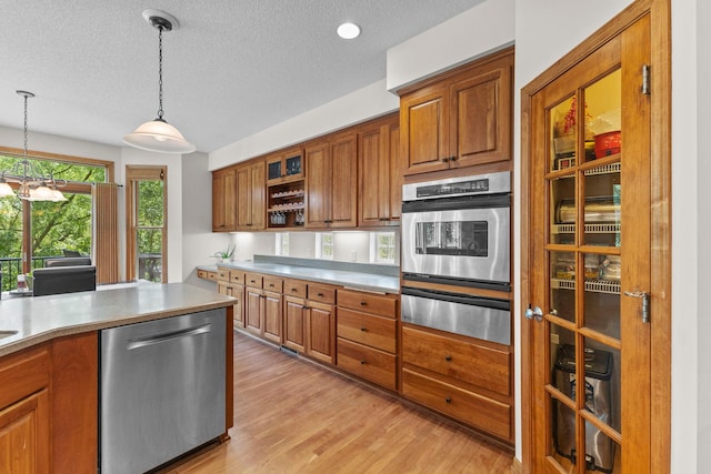 17397 73rd Pl N, Maple Grove, MN 55311 - kitchen featuring stainless steel appliances, a warming drawer, brown cabinetry, a textured ceiling, and light wood finished floors