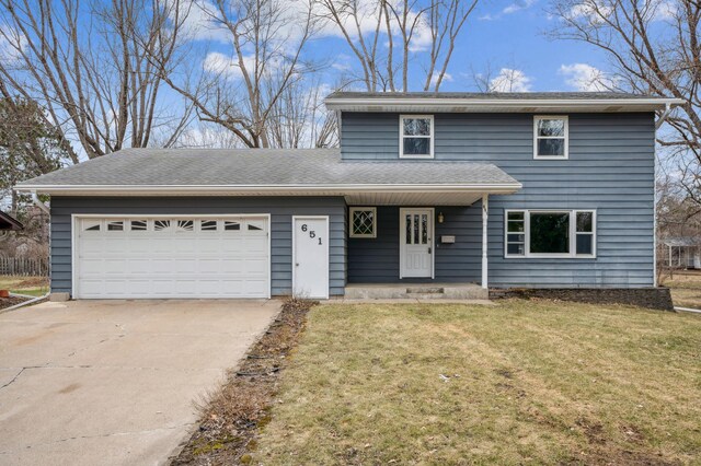 traditional-style house featuring a front lawn, an attached garage, and concrete driveway