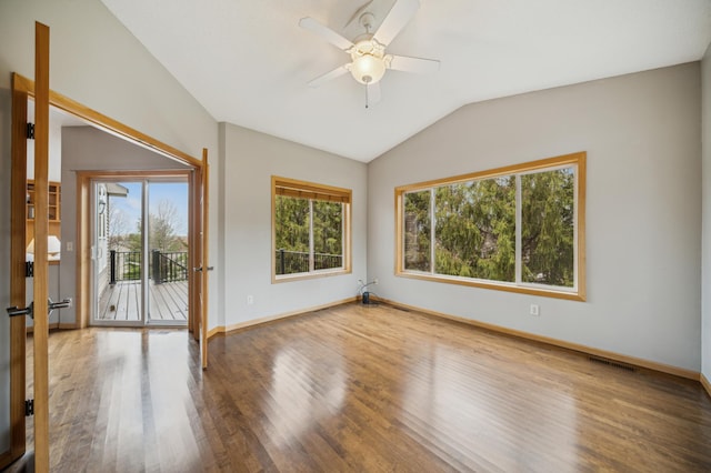 empty room with plenty of natural light, lofted ceiling, visible vents, and wood finished floors