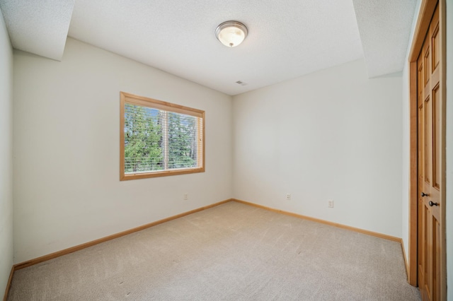 unfurnished bedroom featuring baseboards, a textured ceiling, and light carpet