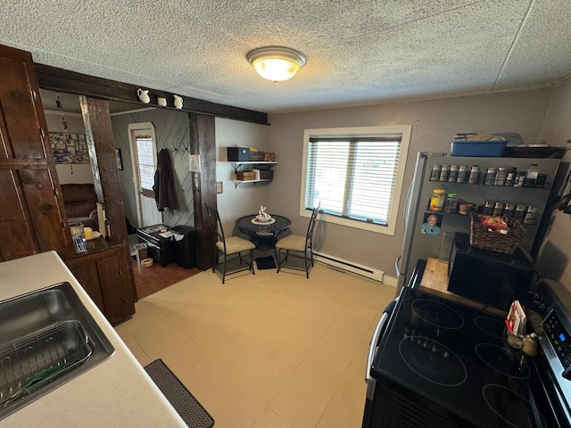kitchen featuring a wealth of natural light, a baseboard radiator, freestanding refrigerator, and black electric range