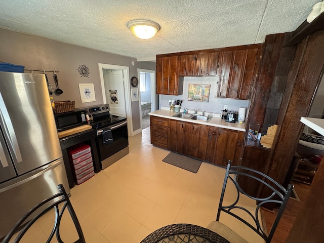 kitchen with light floors, light countertops, stainless steel appliances, a textured ceiling, and a sink
