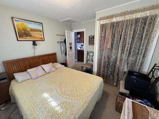 bedroom featuring a textured ceiling, attic access, and carpet