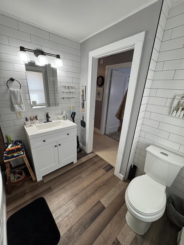 bathroom featuring vanity, tile walls, toilet, and wood finished floors