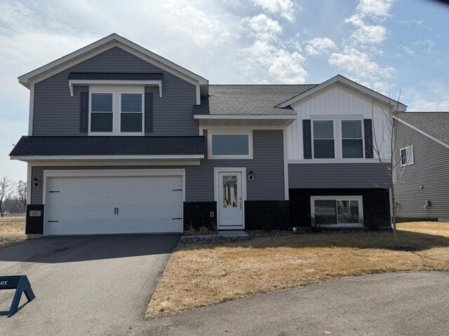 view of front facade featuring a garage, aphalt driveway, roof with shingles, and board and batten siding
