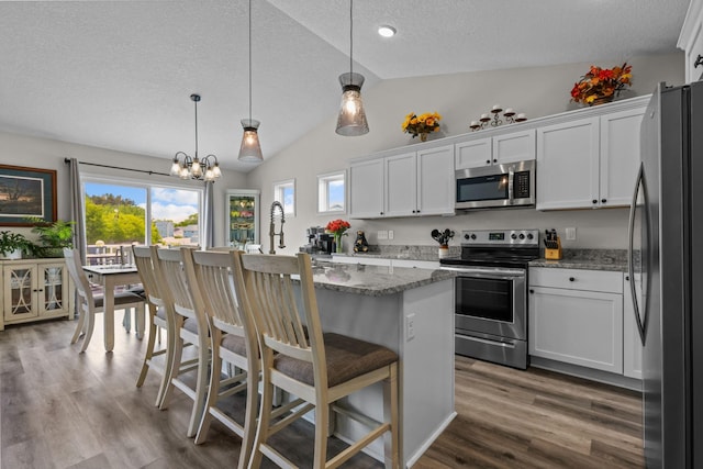 941 Whiskey Rd NW, Isanti, MN 55040 - kitchen featuring stainless steel appliances, a textured ceiling, vaulted ceiling, white cabinetry, and wood finished floors