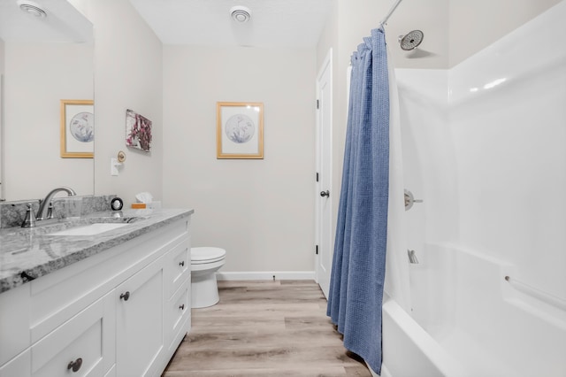 941 Whiskey Rd NW, Isanti, MN 55040 - full bathroom with vanity, toilet, wood finished floors, shower / bathtub combination with curtain, and baseboards