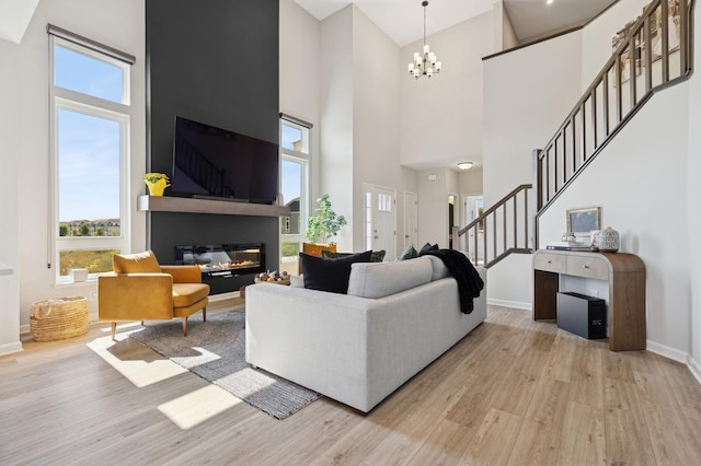 6767 Bluestem Way, Minnetrista, MN 55331 - living area featuring a high ceiling, light wood finished floors, stairway, healthy amount of natural light, and a glass covered fireplace