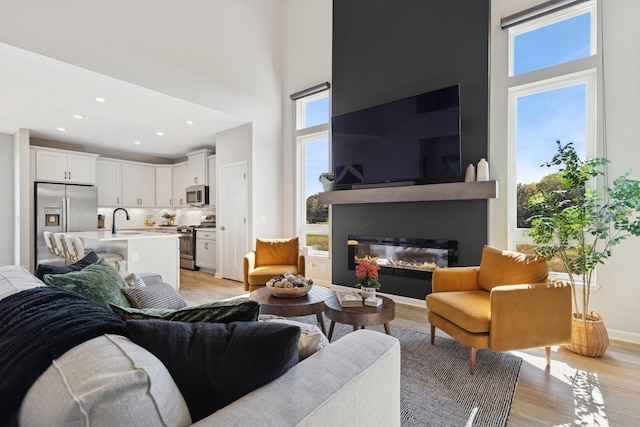 6767 Bluestem Way, Minnetrista, MN 55331 - living room featuring a high ceiling, light wood-style floors, a glass covered fireplace, and recessed lighting