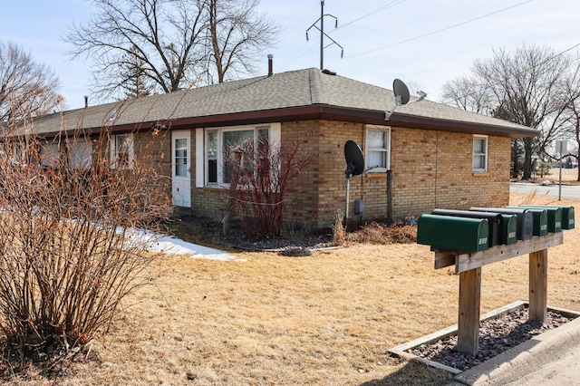 view of property exterior with a shingled roof and brick siding