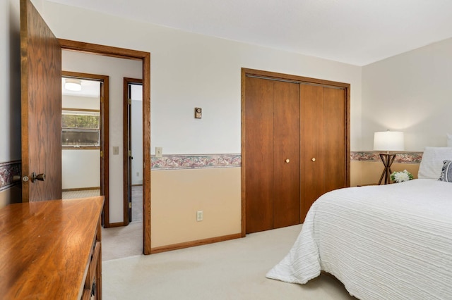 bedroom with a closet, light colored carpet, and baseboards