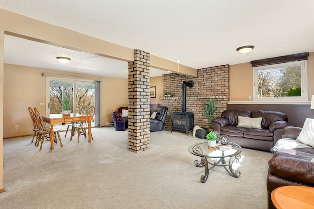 carpeted living room featuring ornate columns, a wood stove, baseboards, and a baseboard heating unit